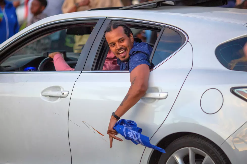 A man waves a blue bandana, symbol of the Crips gang, from a car in the street on April 11, 2019 in Los Angeles, California. (Photo by David McNew/Getty Images)