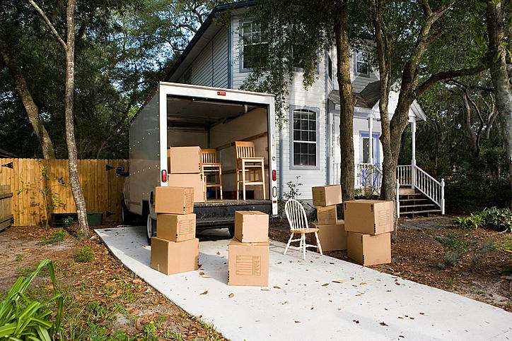 Moving van with cardboard box and chairs by house