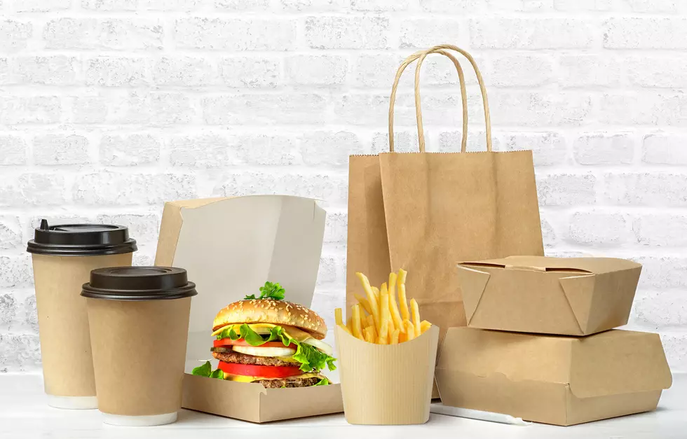 Fast food big lunch set of tasty hamburger, french fries, paper coffee cups, brown paper bag and box on the table on white brick wall background.