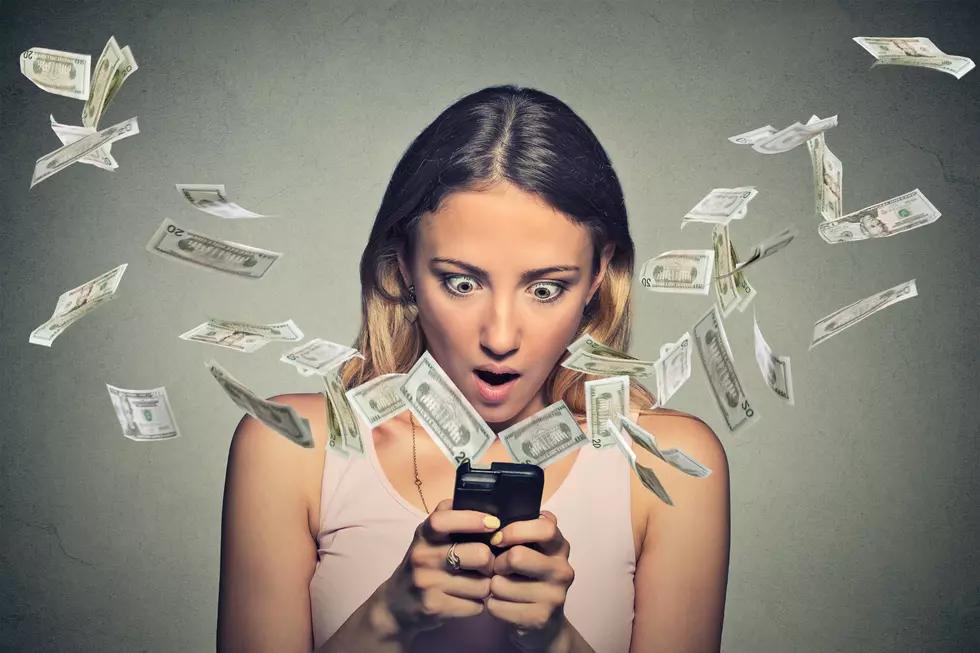Shocked young woman using smartphone with dollar bills flying away from screen