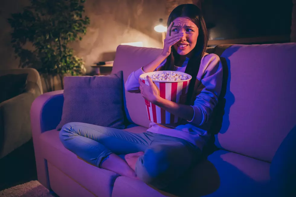 Photo of homey chinese lady eat popcorn movie night watch horror scary movie hiding eyes afraid look on blood sit cosy couch casual outfit dark living room indoors