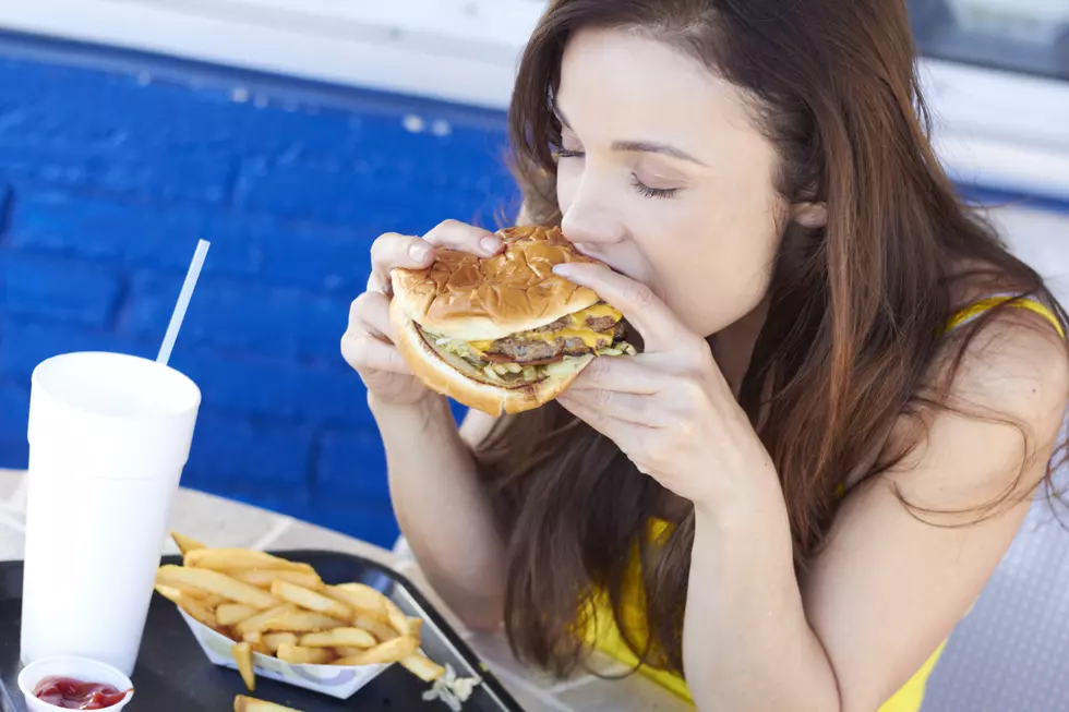 Dark haired woman eating a fast food burger and fries