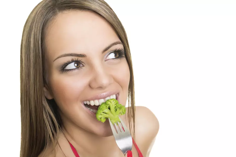 Happy young woman eating broccoli