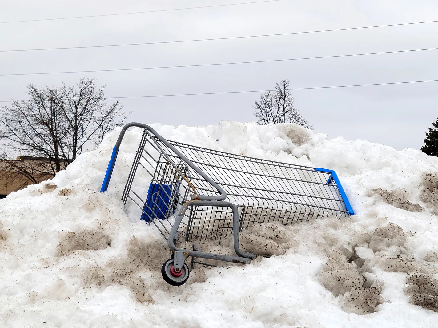 Half-buried shopping cart in a dirty snow bank