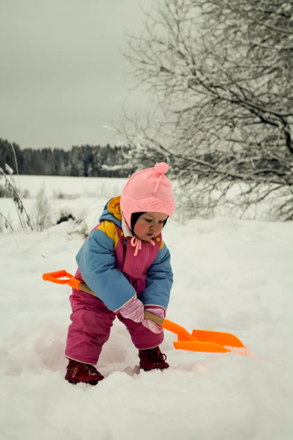 Little Girl Digging Snow with Toy Shovel