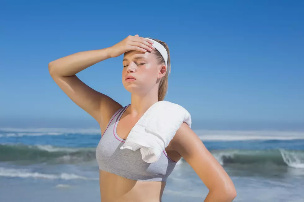 Sporty blonde standing on the beach with towel on a sunny day