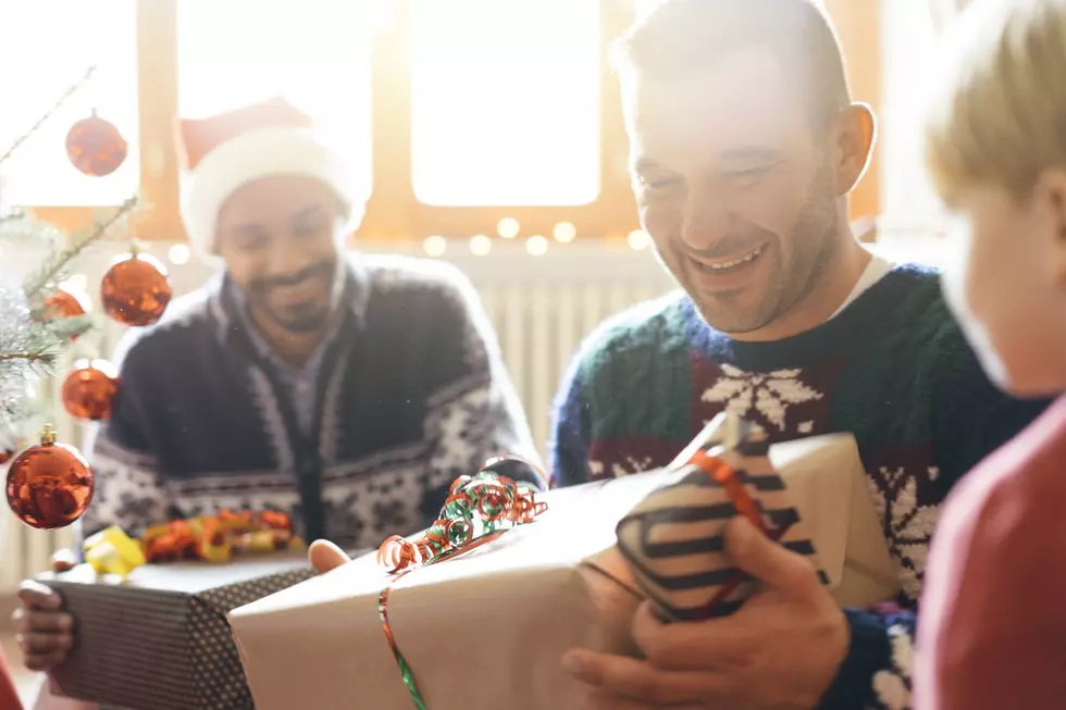 two dads exchange presents with young child