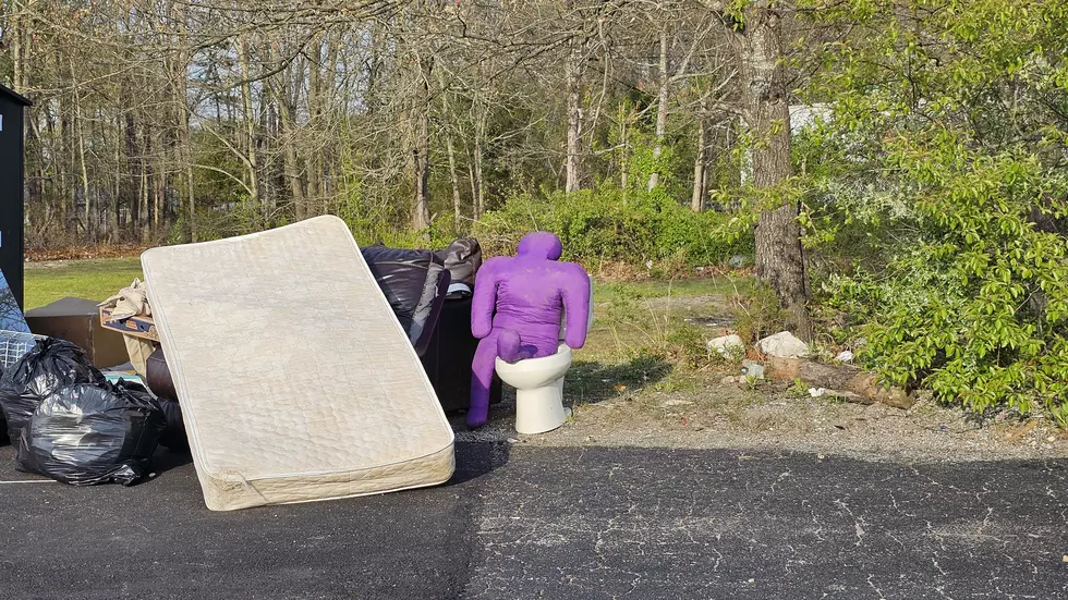 A purple man on a toilet near a clothing donation bin in Galloway NJ