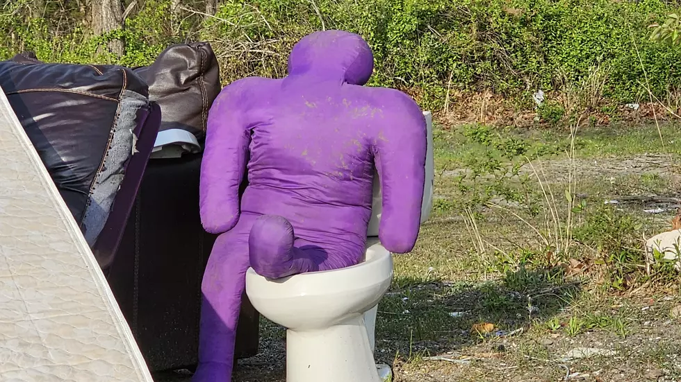 A purple man on a toilet near a clothing donation bin in Galloway NJ