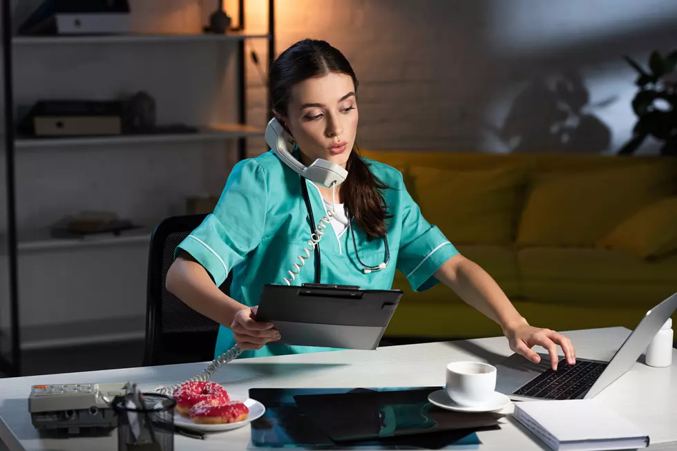 nurse in uniform talking on telephone and holding clipboard during night shift
