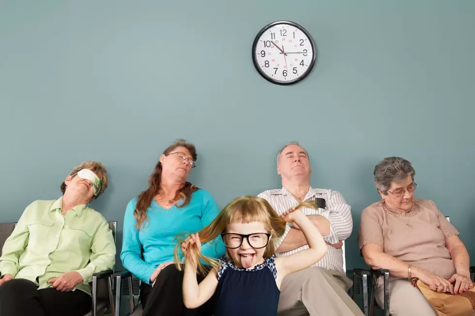 A group of people sit falling asleep beneath a clock as a feral child runs amok in a Michigan Secretary of State Office