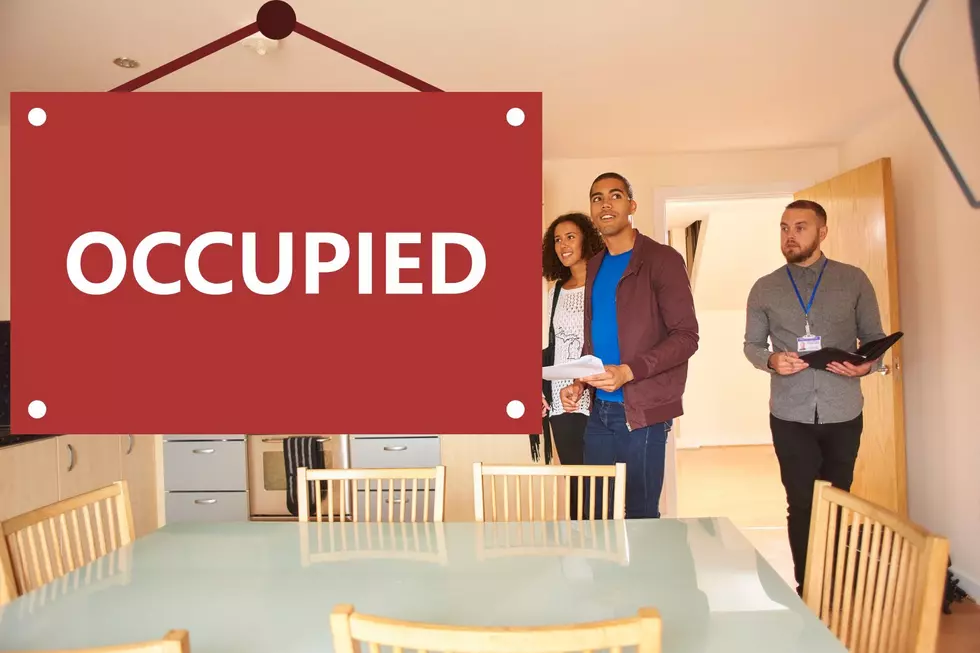 Renters looking excited while touring an apartment without having seen the OCCUPIED sign hanging within.