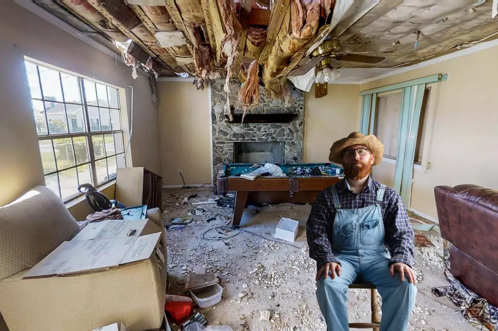 A rundown home is seen with a single man wearing straw hat stacking his claim in the middle of the abandoned home.