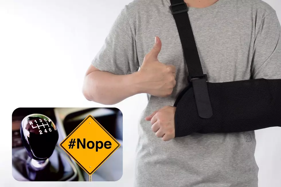 A man in a sling gives the thumbs up with an image of a manual transmission next to a sign that says #NOPE