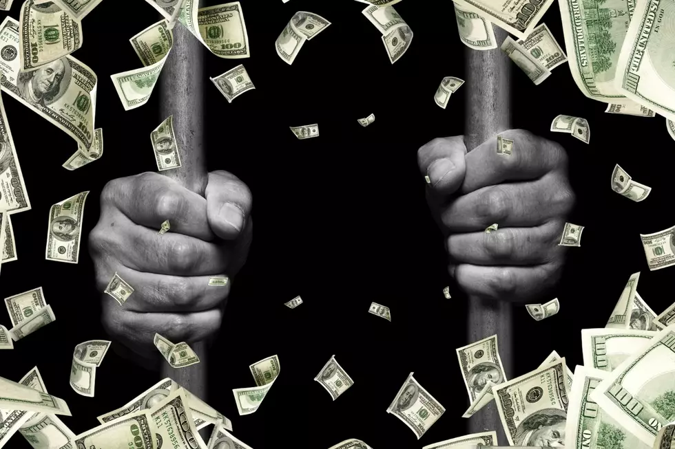 A pair of hands is seen holding bars from inside a prison cell with money falling around the scene