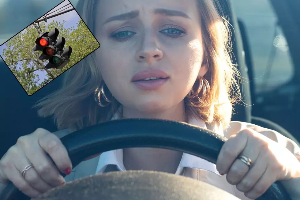 A woman holds onto the steering wheel nervously as she waits at a red light