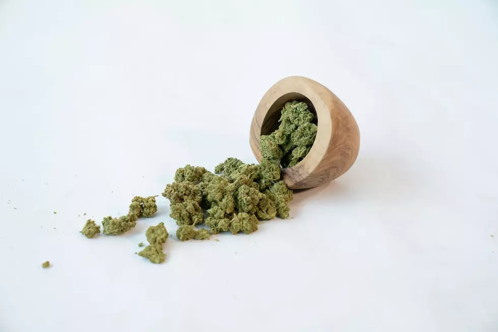 A bowl of marijuana buds spills its contents onto a white surface.