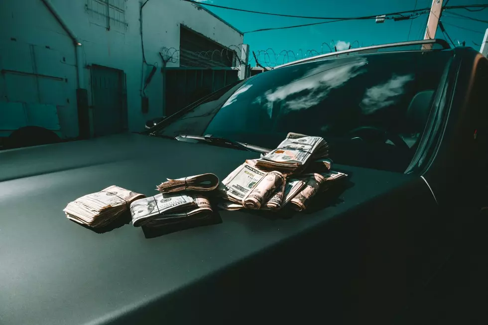 The hood of a car is seen with wads of cash resting upon it.