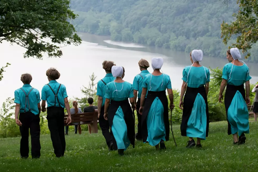 A group of Amish young men and women walk towards a lake.