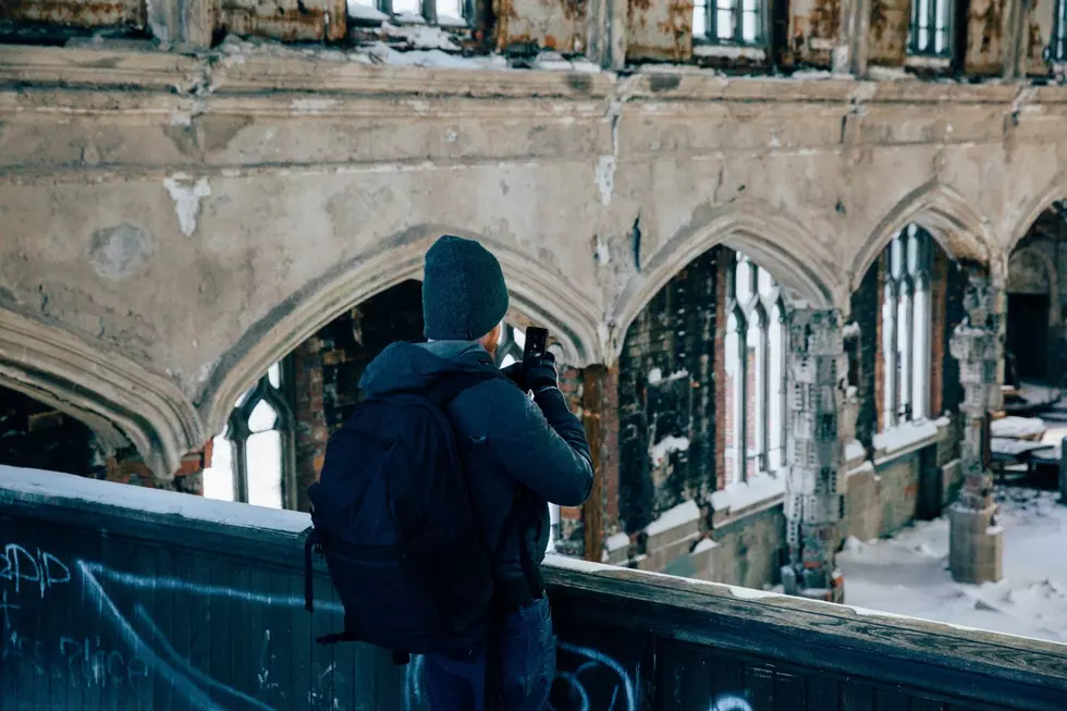 A person stands inside a vacant building while taking a picture in Detroit, Michigan.