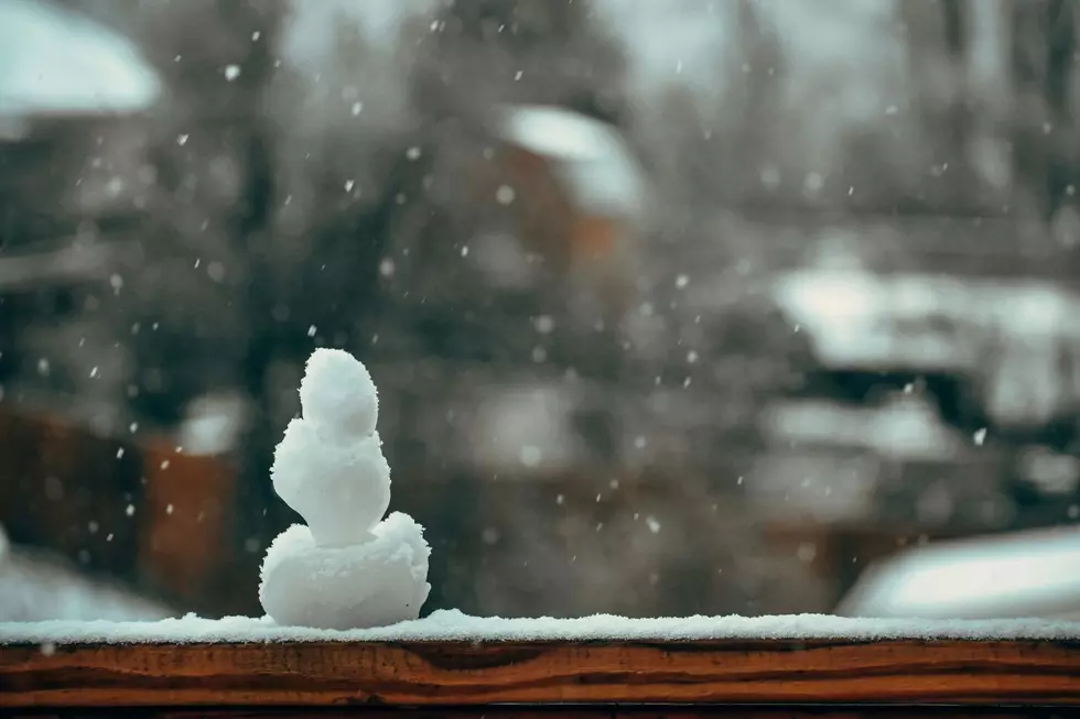 A tiny snowman sits on a window ledge.