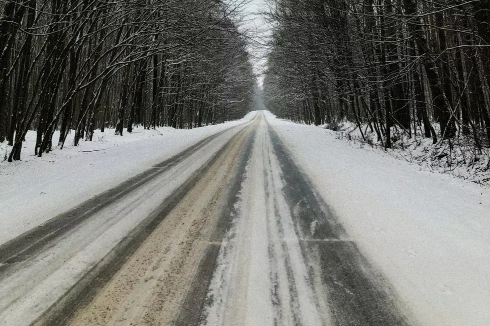 A snow covered road surrounded by woods.