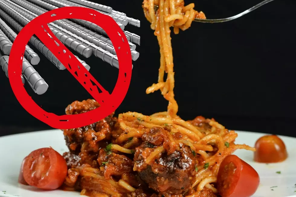 A fork lifts a helping of spaghetti from a plate with metal bars appearing in the upper left corner with a red circle and a line through it.
