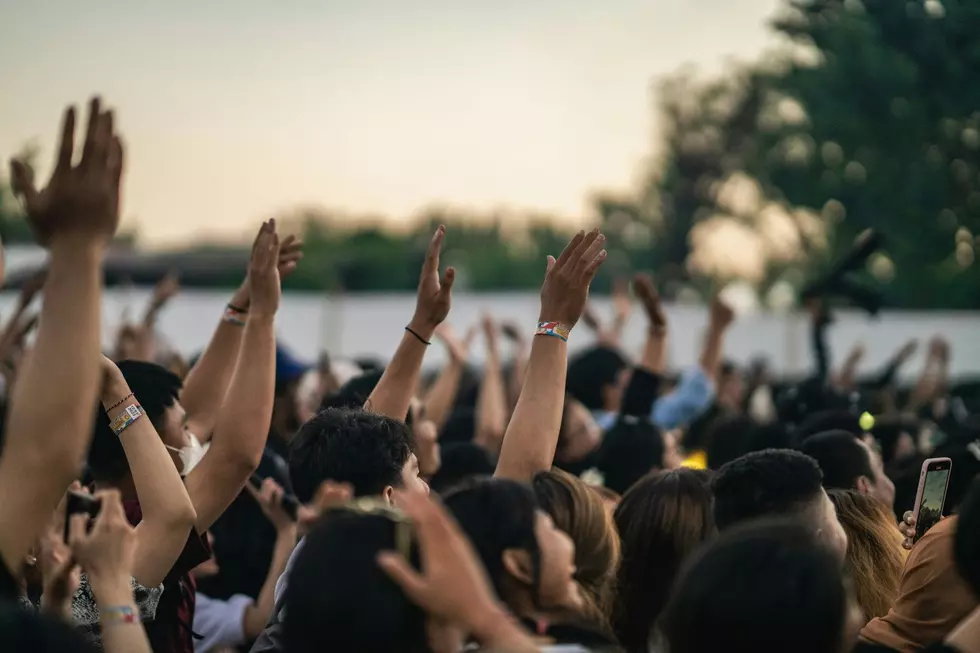 A crowd of concert goers raise their hands to the music.