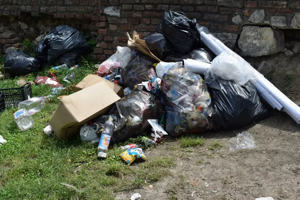 A pile of trash sitting on grass and gravel.