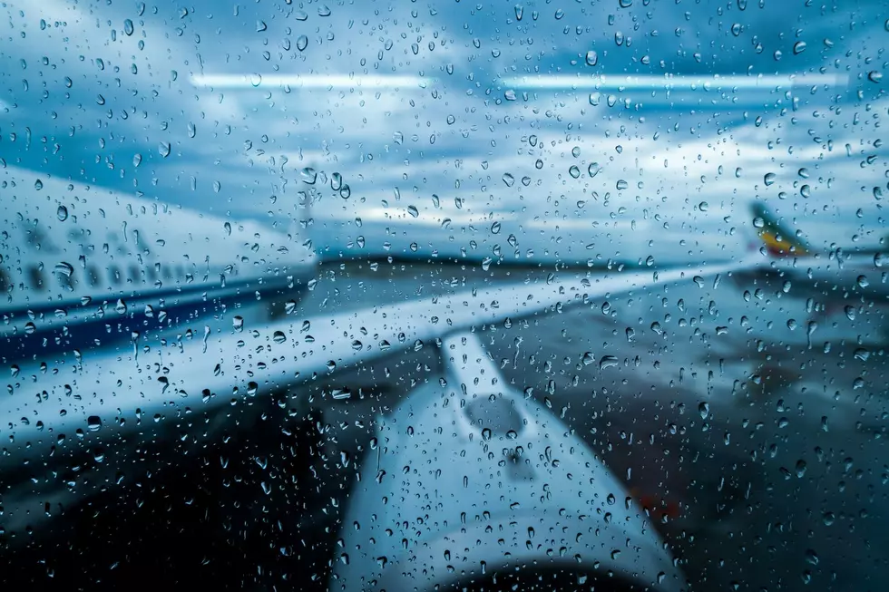 Airplane wing seen through a boarding area window with raindrops.