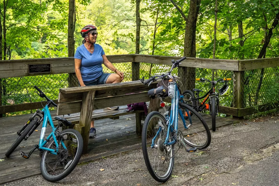 A woman stands next to a pair of bikes while resting along the Michigan Air Line Trail.