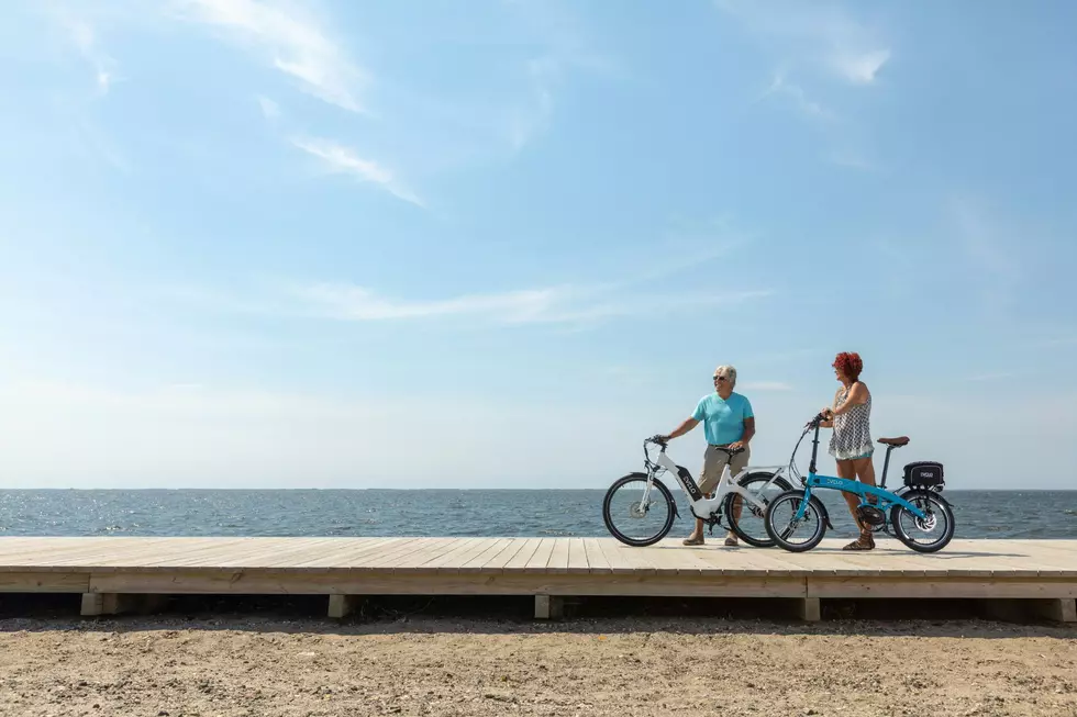 A man and woman on a boardwalk with e-bikes.
