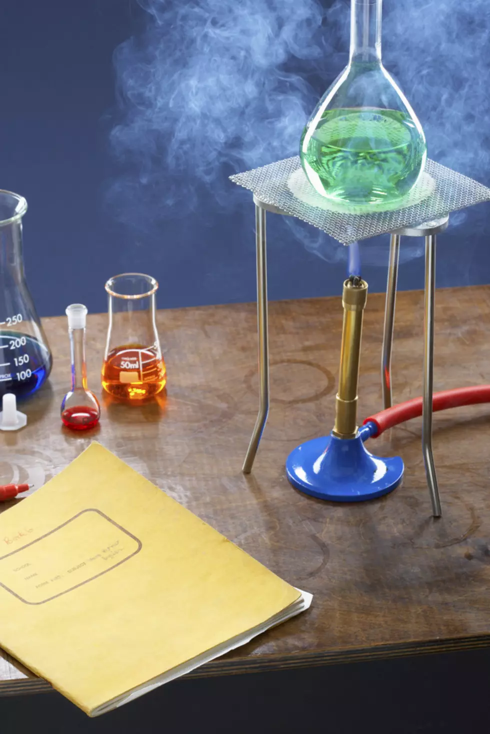 Bunsen burner heating flask with science equipment in laboratory