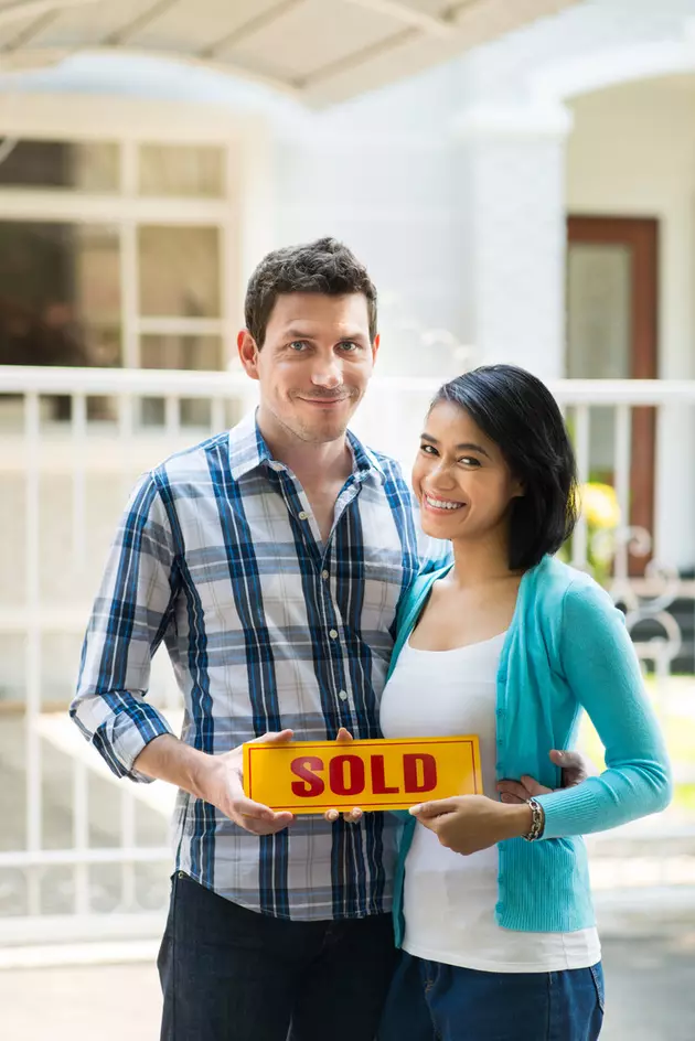 Young multiracial couple holding sold-sign