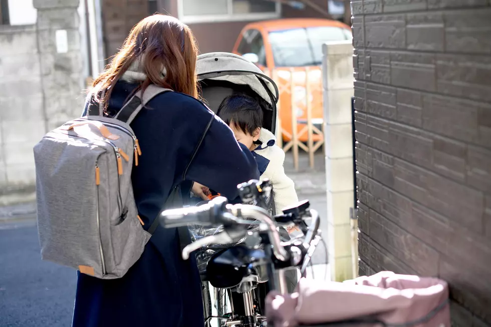 A young Asian mother seats her young child in a bicycle child seat