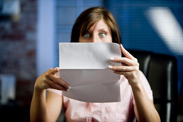 A woman looking at her mail (letter or bills)  in disbelief, shock!