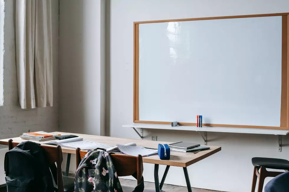 empty desk in a classroom with a dry erase board behind it