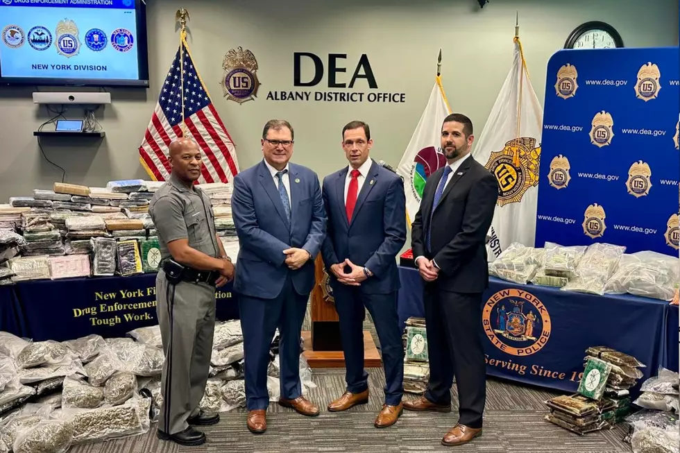 Officials pose in front of drugs, money, and guns seized in a recent large-scale bust (New York State Police via Facebook)