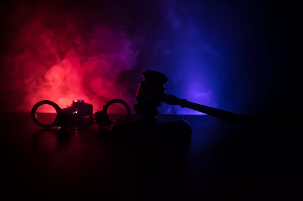Legal law concept. Silhouette of handcuffs with The Statue of Justice on backside with the flashing red and blue police lights at foggy background. Selective focus