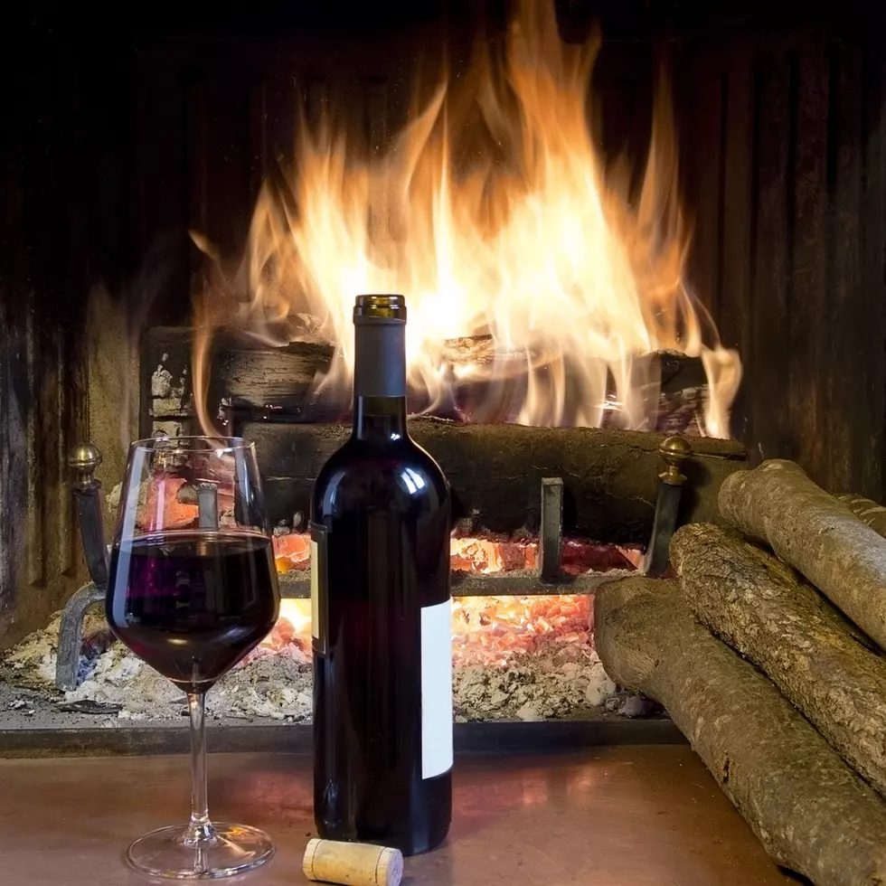 celebrate with a glass of wine, a bottle, in front of a fireplace