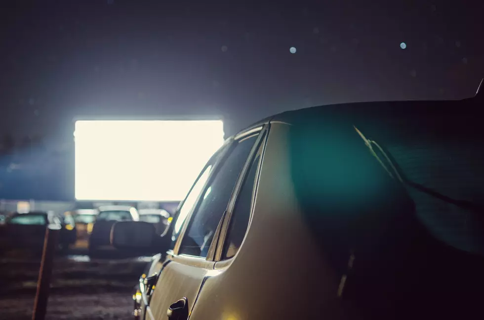A parked car at a drive-in movie theater.