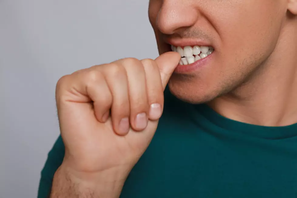 Man biting his nails on grey background, closeup. Bad habit