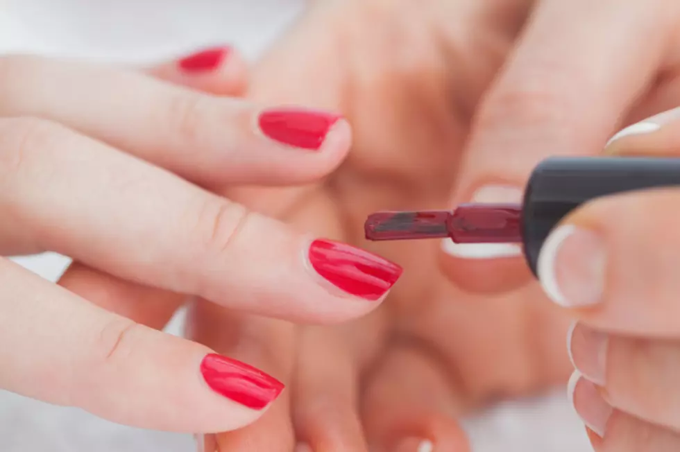 Details shot of hands applying red nail varnish to nails