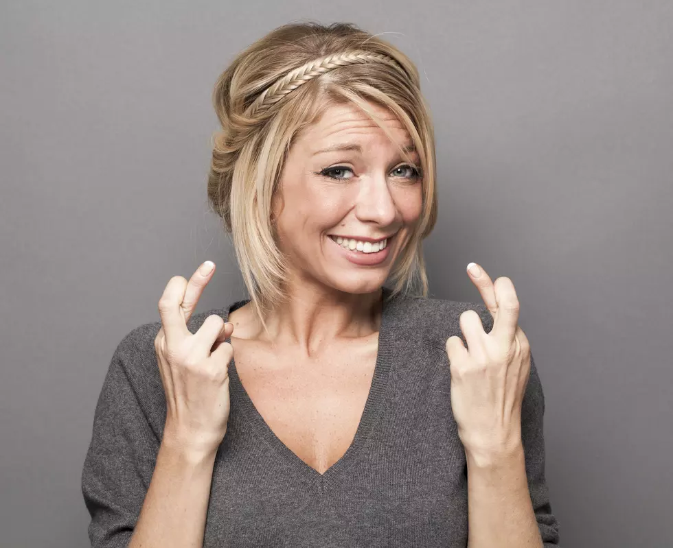 trendy blond girl trusting faith in crossing her fingers tight