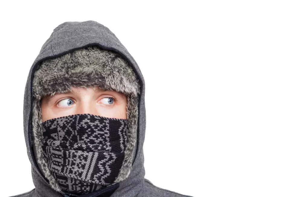 Young man in hat, scarf and hood hiding from cold