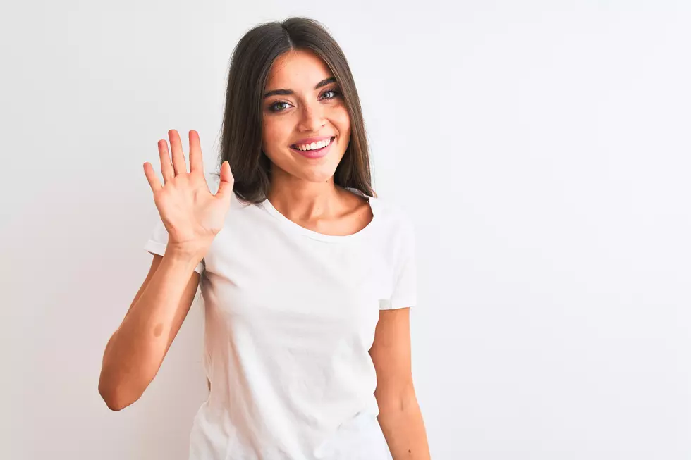 Young beautiful woman wearing casual t-shirt standing over isolated white background Waiving saying hello happy and smiling, friendly welcome gesture