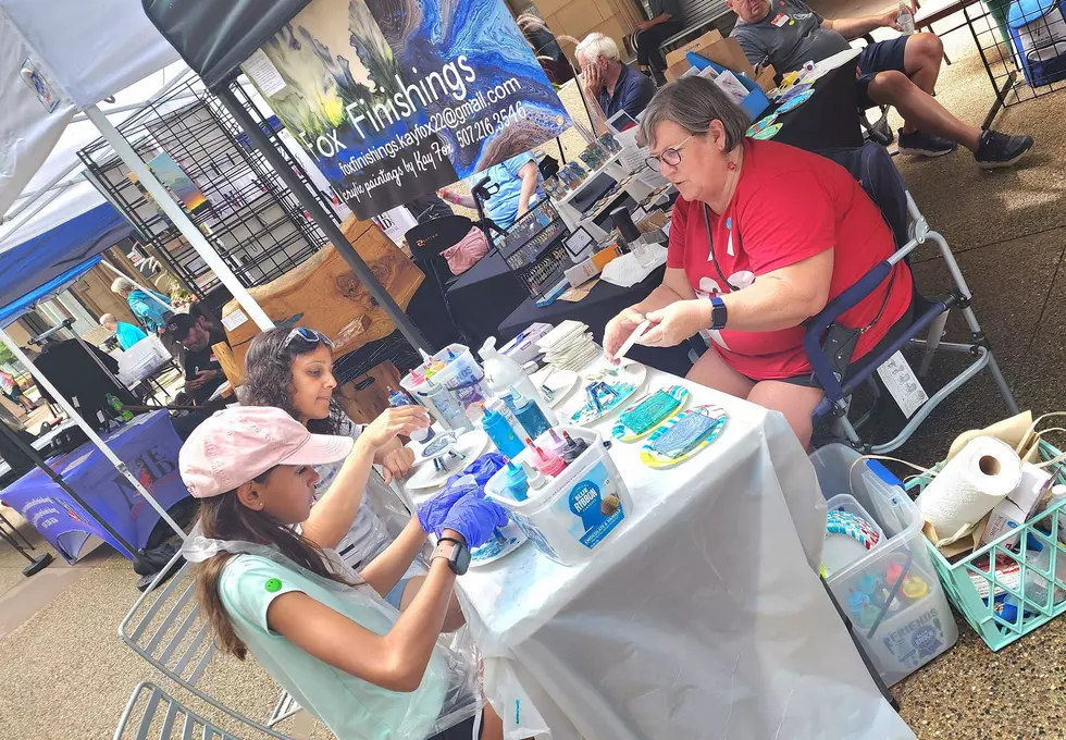 a vendor teaching two people how to pain at the med city art festival in rochester, mn