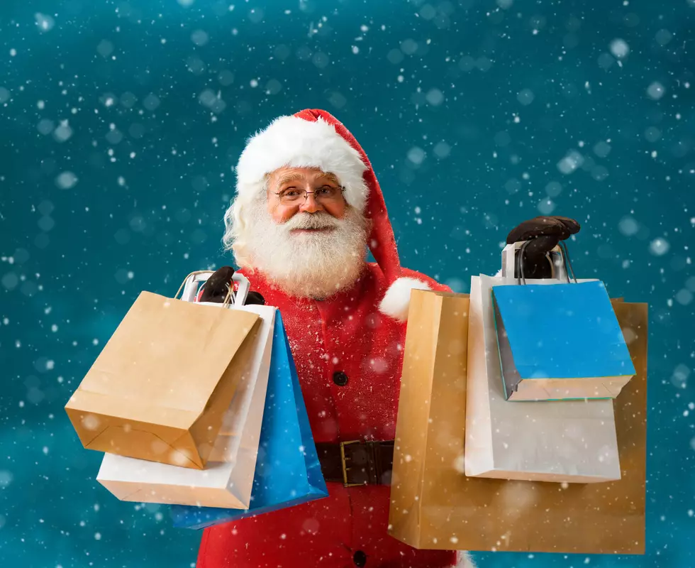 Cheerful Santa Claus outdoors in snowfall holding shopping bags