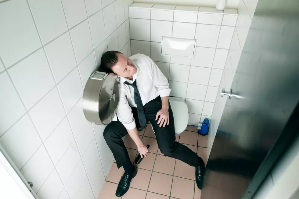 Young man is sitting drunk on a toilette, presumably he is in a club