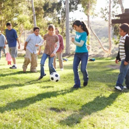 Children (9-14) playing soccer in park